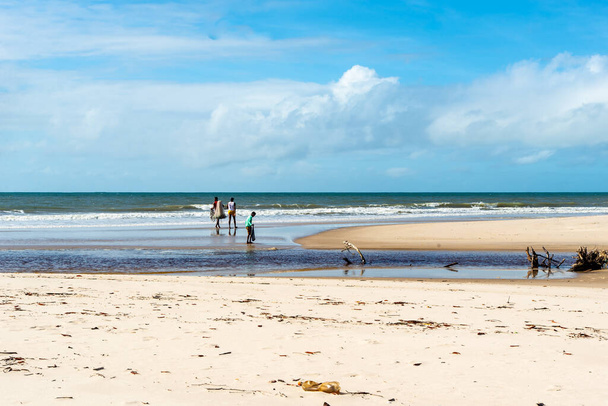 Οι ψαράδες φαίνονται να περπατούν στην παραλία με φόντο τη θάλασσα και τον γαλάζιο ουρανό. Παραλία Guaibim στην πόλη Valenca, Bahia, Βραζιλία. - Φωτογραφία, εικόνα