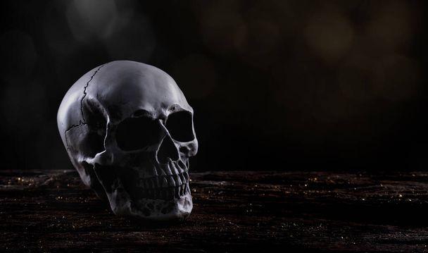 Crâne humain Halloween sur une vieille table en bois sur fond noir. Forme de l'os du crâne pour la tête de mort à la fête d'Halloween qui montrent horreur mal dent peur et effrayant avec de la fumée de brouillard, copier l'espace - Photo, image
