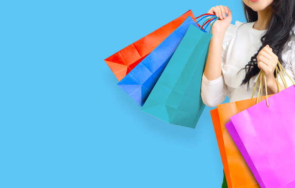 happy young asian woman with shopping bags on blue background - Фото, зображення