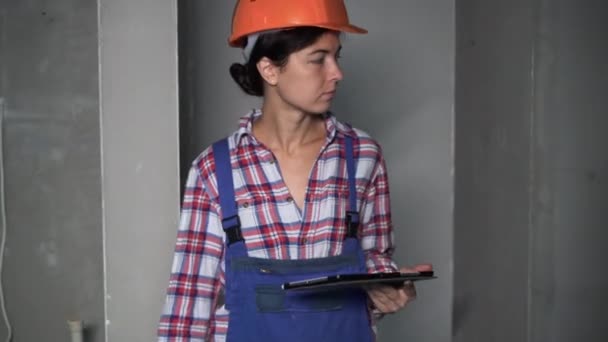 jonge vrouwelijke burger engeneer werknemer project manager met tablet pc op een binnen bouwplaats, vrouw bouwer werken met tablet. reparatie, bouw en bouwconcept - Video