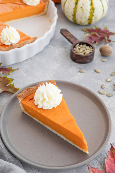 Traditional pumpkin pie with whipped cream and cinnamon on dark wooden background. Homemade pastry for Thanksgiving or Halloween. Copy space - Φωτογραφία, εικόνα