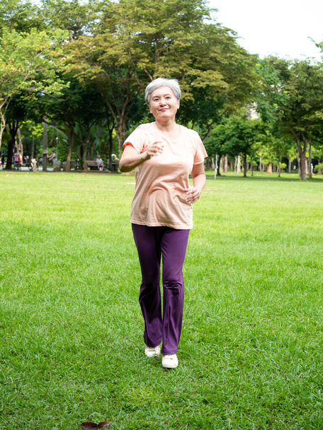Porträt der reifen asiatischen Frau der 60er Jahre in Sportbekleidung beim Joggen im Park im Freien. - Foto, Bild