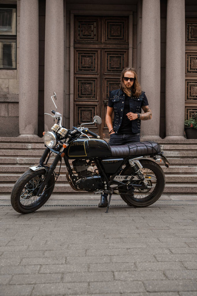 Prise de vue de motard brutal avec barbe et poils longs conduisant moto. - Photo, image