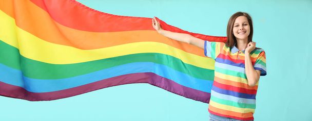 Mujer joven con bandera LGBT sobre fondo turquesa - Foto, imagen