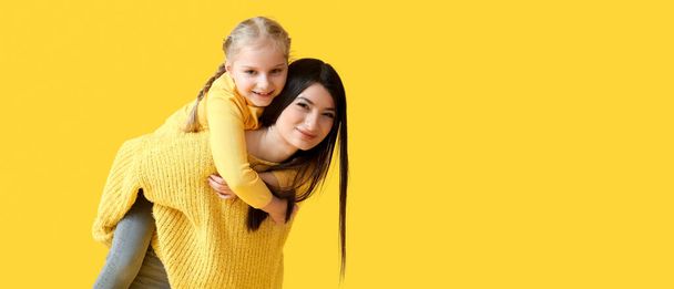 Boldog anya és kislánya meleg pulóverben sárga háttérrel, szöveges szöveggel - Fotó, kép