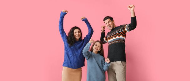 Happy family in warm sweaters on pink background - Foto, afbeelding