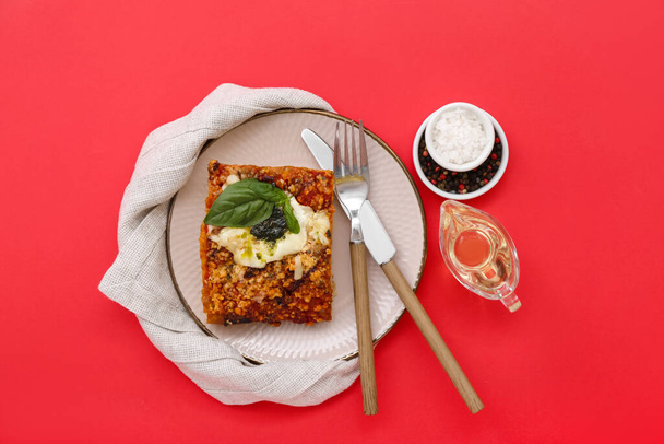 Plate of tasty Italian pie with mozzarella, pesto sauce, spices and oil on red background - Valokuva, kuva