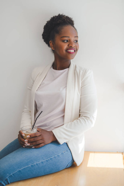 Mujer de negocios afroamericana elegante pensativa que se relaja en la cafetería con café con leche helada durante el trabajo a distancia. Esperando la reunión. Relajante en descanso descansando en - Foto, Imagen
