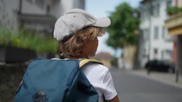 Achterkant van kind lopen in stedelijke straat draagt rugzak - Video