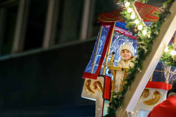 Kleine Vorschulmädchen reiten auf dem Riesenrad-Karussell auf dem Weihnachtsmarkt oder Markt, im Freien. Glückliches Kleinkind hat Spaß auf traditionellem Familien-Weihnachtsmarkt in Deutschland. - Foto, Bild
