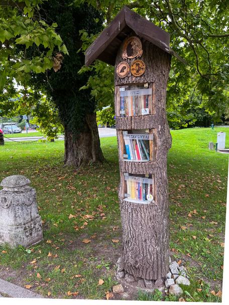 Een manier om boeken te populariseren. Een speciale boomstam met ruimte voor boeken met de inscriptie "take, read, give back" staand in het park in Rudy, Polen op 3 september 2022. - Foto, afbeelding