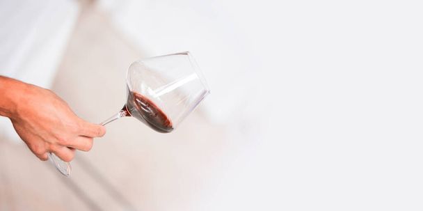 Glass of red wine in hand at a special event, a specific tasting of alcoholic beverages. - 写真・画像