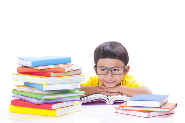 Mignon petit garçon lit un livre tout en portant des lunettes
. - Photo, image