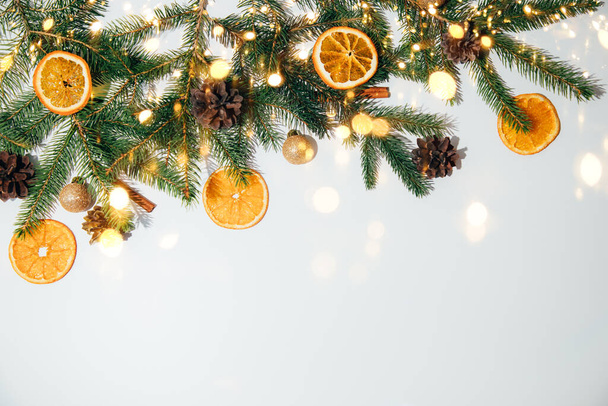 Anno nuovo, sfondo natalizio. Decorazione di anno nuovo su uno sfondo bianco con rami di un abete, pigne e fette di arancione secco. Posa piatta - Foto, immagini