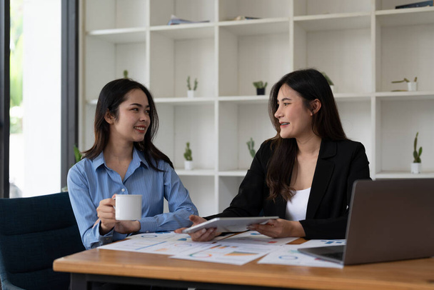 Две азиатки-деловые женщины улыбаются счастливыми и уверенными в себе. Работать вместе с улыбкой на лице в офисе. - Фото, изображение