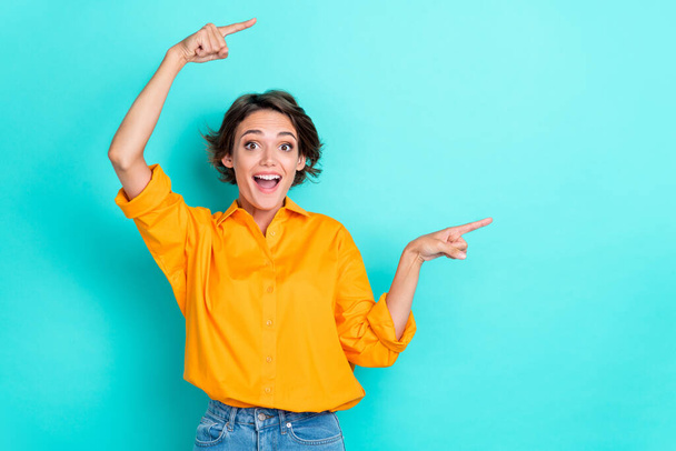 Portrait of ecstatic pretty gorgeous girl wear yellow blouse directing empty space unexpected news isolated on turquoise color background. - Fotoğraf, Görsel