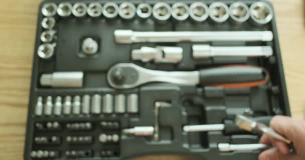Auto mecánico conecta una extensión de metal a una pequeña llave de trinquete, añade un poco. Demostración del trabajo de la clave, un conjunto de herramientas en segundo plano, primer plano, vista superior. Imágenes de alta calidad 4k - Metraje, vídeo