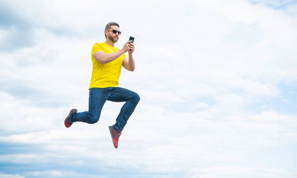 man jump and chatting on smartphone on sky background. copy space. - Photo, image