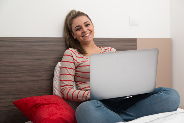 Donna felice in camera da letto con il computer portatile
 - Foto, immagini