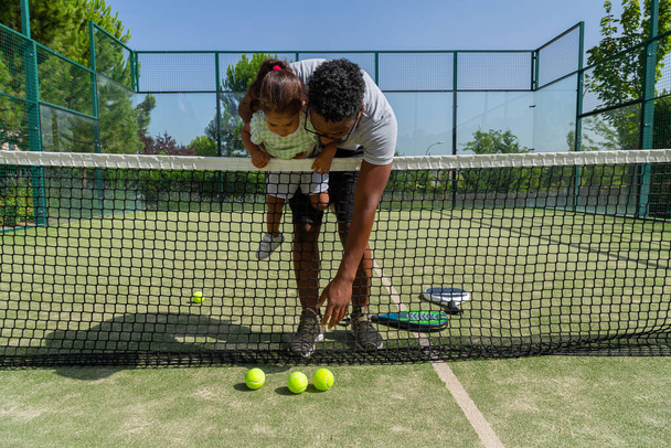 Чорний батько і дочка на тенісному корті
 - Фото, зображення