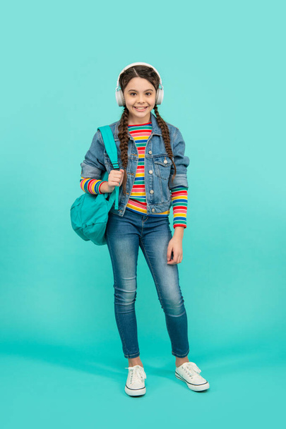 Happy girl teenager listening to music in headphones blue background, education. School education. Non-formal education. - Φωτογραφία, εικόνα