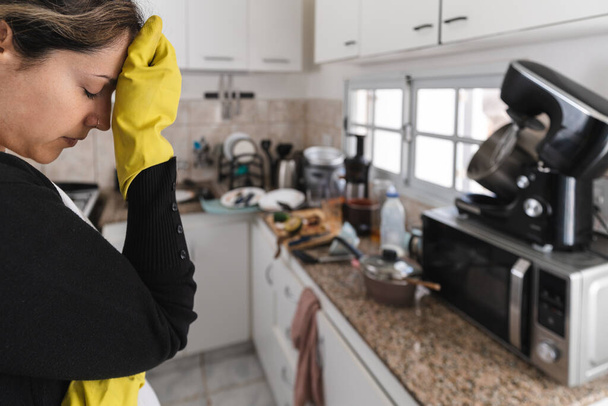 Femme portant des gants de nettoyage inquiet pour sa cuisine sale. Concentration sélective - Photo, image