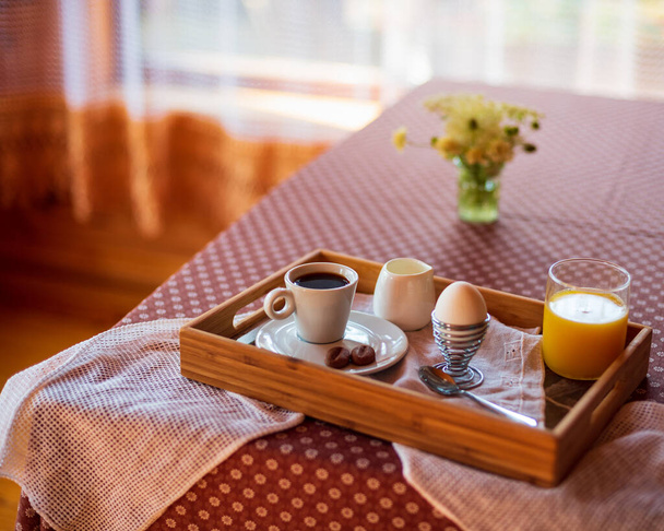 Ontbijt met gekookt ei, sinaasappelsap en koffie. Zonnige ochtend. - Foto, afbeelding