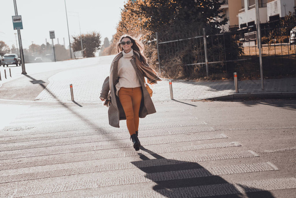 Photo of sweet pretty woman wear grey coat dark glasses crossing road running courses enjoying morning sunshine outside urban city street. - Fotó, kép