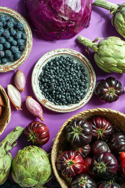 morado y rojo, verduras violetas sobre el fondo morado, vista superior. alcachofa púrpura, tomates, cebollas, arándanos, ensalada, contienen antocininas, que se encuentran en la dieta de Okinawa, que mantienen la salud - Foto, Imagen