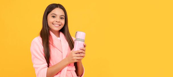щаслива дівчина-підліток в домашньому махровому халаті з пляшкою термос, вранці. Горизонтальний плакат ізольованого дитячого обличчя, заголовка банера, простір для копіювання
 - Фото, зображення