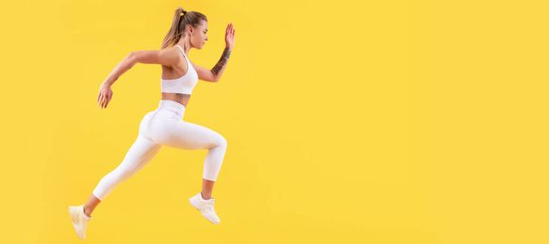 黄色い背景で走るフィットネス女子ランナー。コピースペース。女性ジャンプランニングバナーとともにmockアップコピースペース - 写真・画像