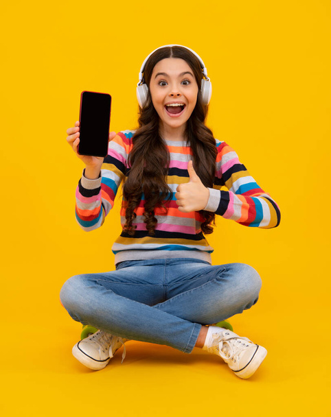 Amazed teenager. Teenager child girl holding smartphone. Hipster girl types text message on cell phone, enjoys online communication, types feedback, Kid showing blank screen mobile phone, mockup - Foto, Imagem