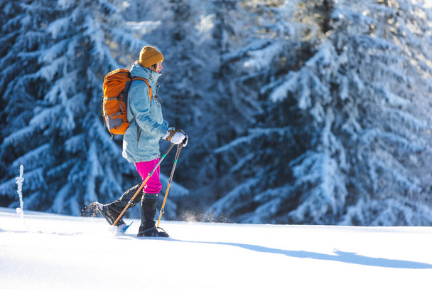 Een vrouw loopt in sneeuwschoenen in de sneeuw, winterwandelen, een persoon in de bergen in de winter, wandeluitrusting - Foto, afbeelding