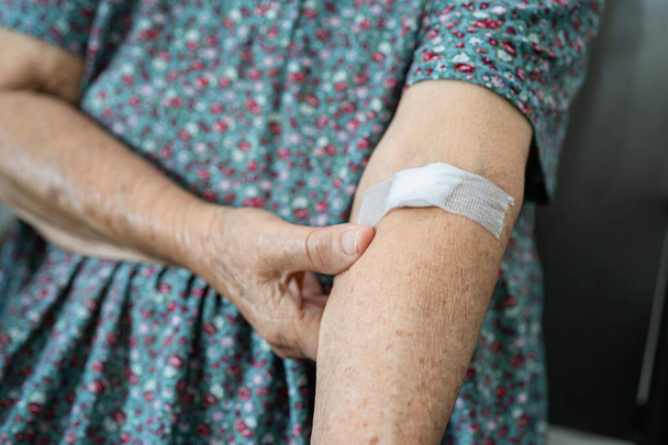 Aziatische senior of oudere oude dame patiënt tonen katoen wol stoppen met bloeden, na bloedonderzoek voor jaarlijkse fysieke gezondheidscontrole tot cholesterol, bloeddruk en suikerspiegel te controleren. - Foto, afbeelding