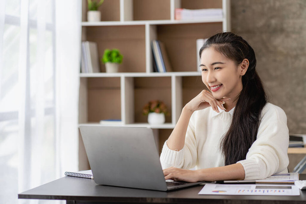 Рассчитывается новое поколение азиатских женщин-бухгалтеров. Привлекательные офисные рабочие сбережения, финансы и экономические концепции для записи блокнотов, размещенных на рабочем столе. - Фото, изображение
