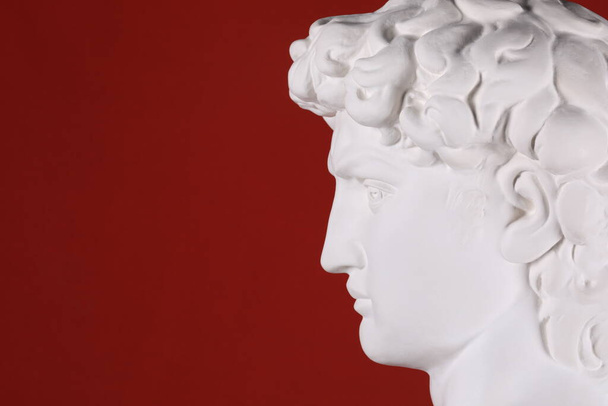 Kırmızı arka planda antik beyaz alçı başlık heykeli - Fotoğraf, Görsel