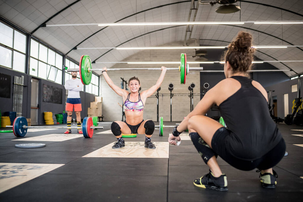 Coach training athletic fit woman indoors gym weightlifting bodybuilding - Fotoğraf, Görsel