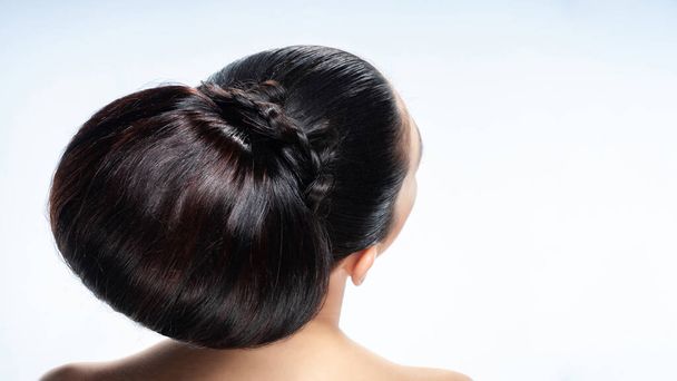 Back view of a young brunette woman. Portrait of a nude young caucasian woman with copy space. Dark hair. Stylish hairstyle. Isolated on a light background - Photo, Image