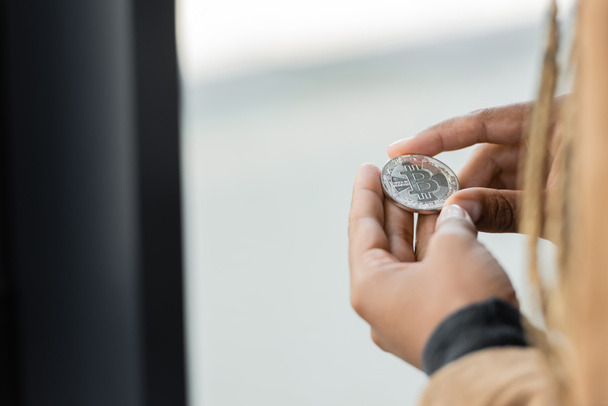 Vágott kilátás afro-amerikai üzletasszony kezében ezüst bitcoin az irodában  - Fotó, kép