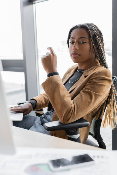 African american businesswoman using laptop and looking away in office  - Fotografie, Obrázek