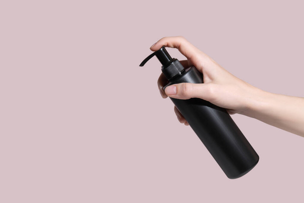 Womens hands press on a black dispenser with a cream. Copy space. Mockup. High quality photo - 写真・画像