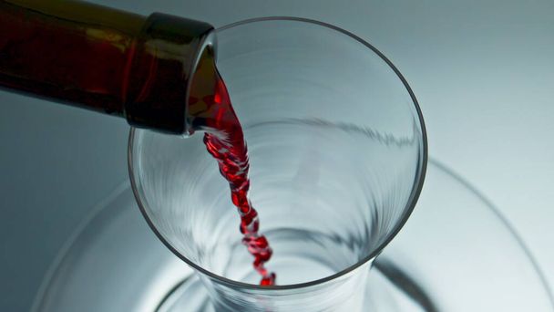 Μπουκάλι λαιμό ρίχνει κόκκινο κρασί decanter closeup. Ακριβό τριαντάφυλλο ποτό πλήρωση μπολ μακροεντολή αργή κίνηση. Μεθυσμένοι ποτό πολυτελείας ρέει κάτω γυάλινα σκεύη πάνω άποψη. Έννοια της διαδικασίας εκρόφησης  - Φωτογραφία, εικόνα