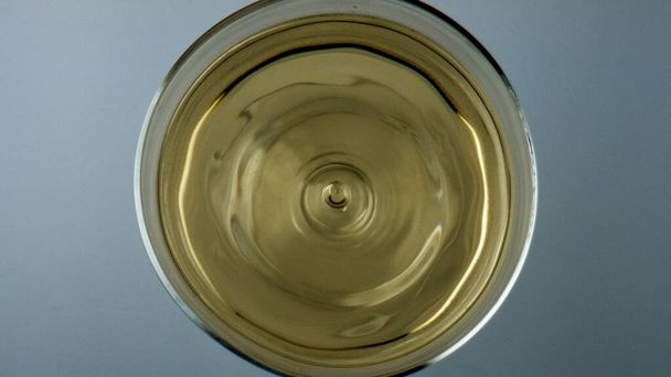 Winery droplet falling glass top view. Grape juice liquid rippling waving in cup. Golden cool sauvignon white wine beverage splashing in transparent goblet. Crystal clear beverage for celebration. - Foto, imagen