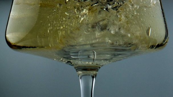 Sparkling wine bubbles glass closeup. Diverse air blobs rising splashing alcohol beverage. Tasty winery product in cup. Golden chardonnay fizzy drink for celebrating anniversary in transparent goblet. - Photo, image