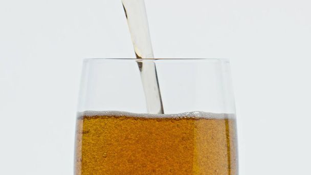 Odświeżające piwo lejące szkło z bliska zwolniło tempo. Alkoholiczka wypełniająca czysty kielich. Odrzutowiec do napojów słodowych spadający w białym tle kontenera. Pojęcie browaru rzemieślniczego  - Zdjęcie, obraz