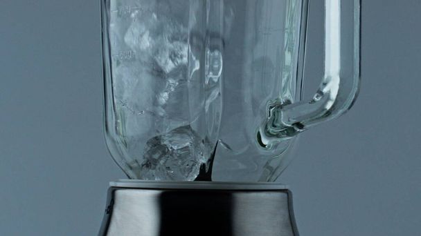 Ice cubes container falling closeup. Cocktail blender filling with iced chunks for summer alcohol beverage. Grinding equipment mixer in kitchen. Evening relaxation party drink preparation concept. - Foto, Bild