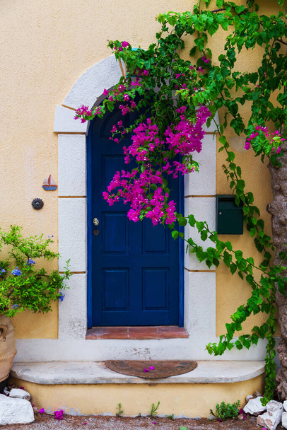 Colorida puerta azul de la casa griega tradicional con paredes amarillas en el pueblo de Asos. Península de Assos famoso y destino de viaje muy popular en Cefalonia, Grecia, Europa - Foto, imagen