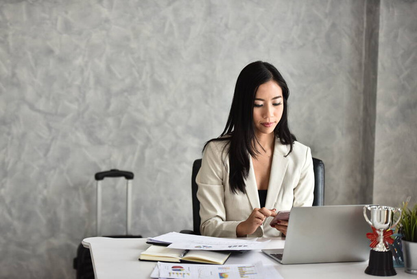 portrét asijské podnikatelky sedící u stolu v kanceláři - Fotografie, Obrázek