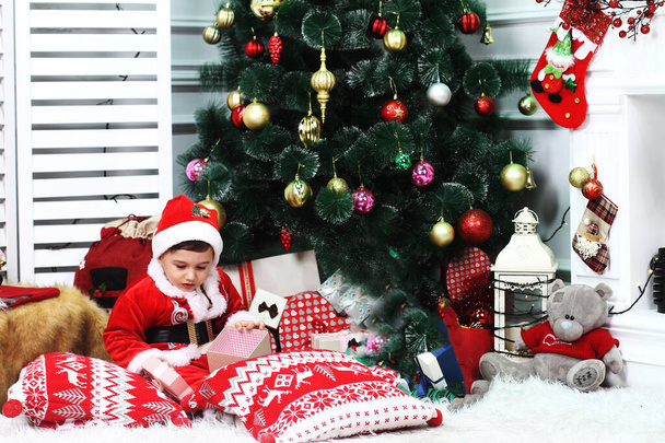 Милая малышка в красном костюме Санта Клауса на диване на Рождество, - Фото, изображение