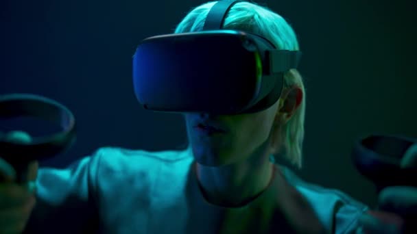Excited man experiencing handheld trackpads videogame closeup. Impressed gamer using gadget for virtual reality on neon background. Futuristic goggles youngster playing. Future technology concept  - Metraje, vídeo